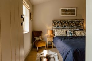 A peek through a partially open bedroom door inside The Dovecote luxury holiday cottage at The Roost, showing a king-size bed.