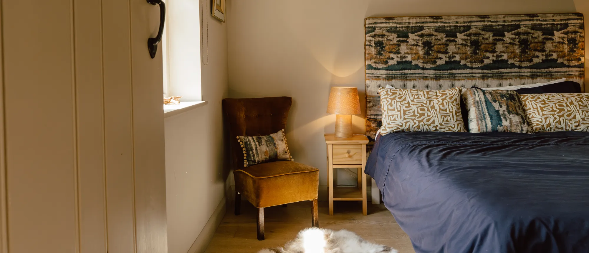 Luxury stone cottage bedroom at The Dovecote featuring a beautifully dressed bed with bright linens and serene, rustic heritage interior design at The Roost Retreats.
