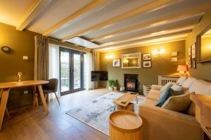 Luxury stone cottage living room at The Rookery featuring a lit wood burner fire, moody interior design, and a cosy seating area at The Roost Retreats.